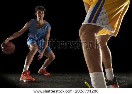 Forward. Two male athletes, competing basketball players in motion isolated over black background. Concept of professional sport, lifestyle, action and motion