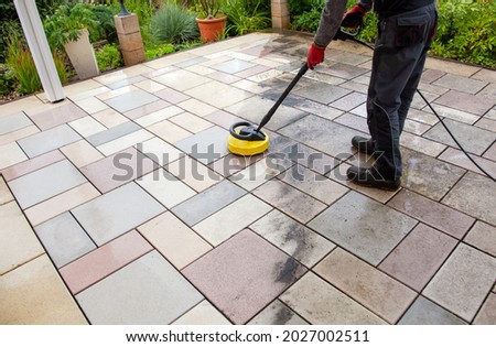 Cleaning stone slabs on patio with the high-pressure cleaner. Person worker cleaning the outdoors floor. clean and dirty Royalty-Free Stock Photo #2027002511