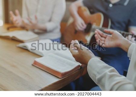 Christian young man group are playing guitar and sings a song from a Christian hymn book and the holy bible with his friends at home, Christian family worship or fellowship group concept Royalty-Free Stock Photo #2027004443
