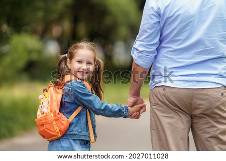 loving family. a caring dad accompanies a little girl with backpacks to school. The child smiles and looks over his shoulder. Close-up. Back to school. the first day of training Royalty-Free Stock Photo #2027011028