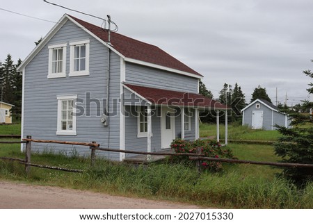 an old school built like a house made of wood in blue colors with wooden windows and a red roof
