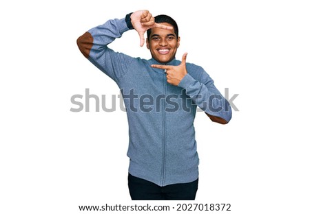 Young handsome hispanic man wearing casual sweatshirt smiling making frame with hands and fingers with happy face. creativity and photography concept. 