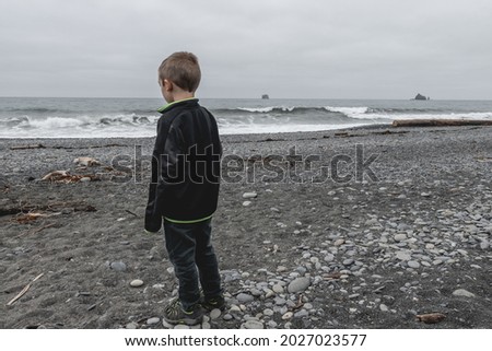 Young boy looking out at the waves on Rialto Beach in Olympic National Park.