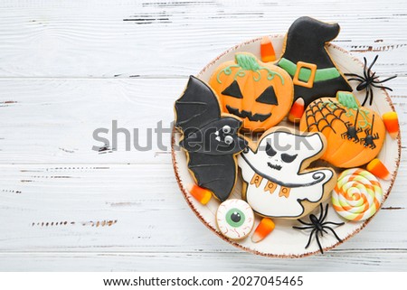Halloween gingerbread cookies with candies and spiders on white wooden table