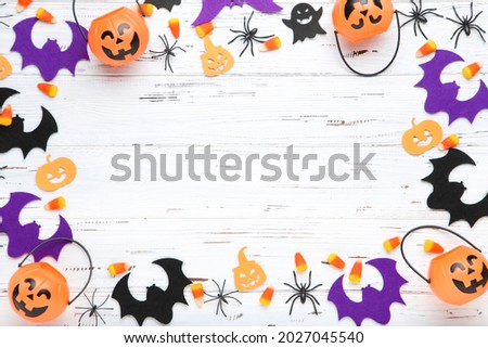 Halloween pumpkin buckets, candies, spiders and paper bats on wooden background