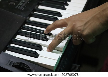 Playing instrumental music using a piano with two fingers. Royalty-Free Stock Photo #2027050784