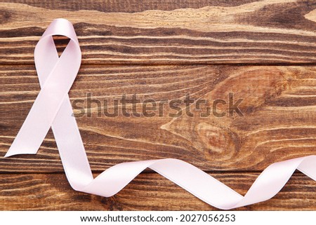 Cancer concept. Pink ribbon on brown wooden background