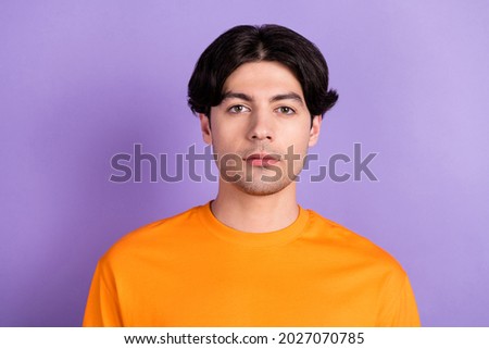 Photo of serious young charming man wear orange casual t-shirt isolated on purple violet color background