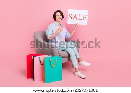 Full length body size photo woman sitting after online shopping keeping sale card isolated pastel pink color background