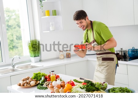 Portrait of attractive funky cheerful guy cooking fresh tasty meal salad having fun making photos at home kitchen indoors