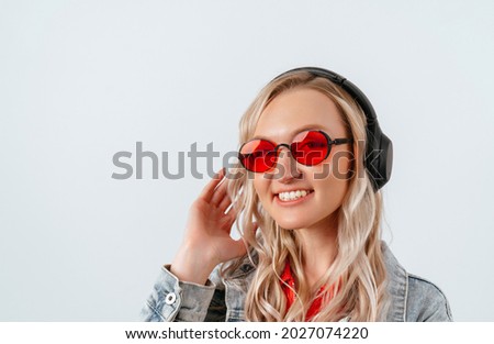 Happy blonde in red glasses and headphones on a white background