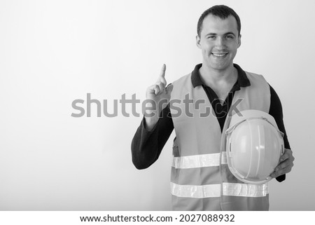 Studio shot of young man construction worker against white background in black and white