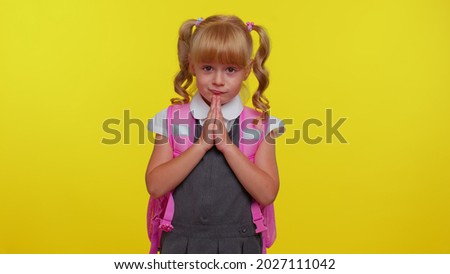 Please, help. Attractive blond teenage student girl kid in school uniform praying, looking upward and making wish, asking with hopeful imploring expression, begging apology. Education, back to school Royalty-Free Stock Photo #2027111042