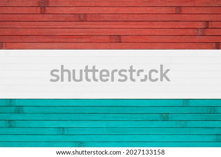 The national state flag of the Grand Duchy of Luxembourg painted on the background of a wooden wall made of bamboo.