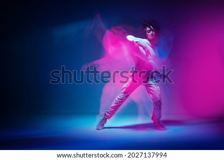 Dancing mixed race girl in colourful neon studio light. Female dancer show expressive hip hop dance. Long exposure