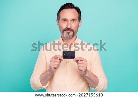 Photo of calm peaceful good mood attractive male hold demonstrate credit card isolated on teal color background