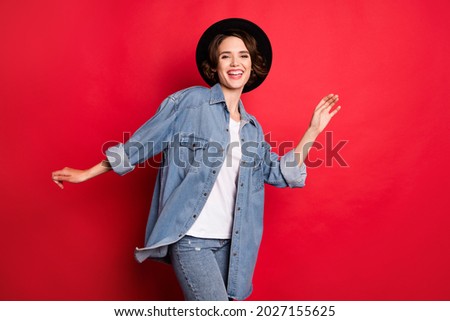 Photo of joyful brunette millennial lady dance wear cap jeans shirt isolated on red color background