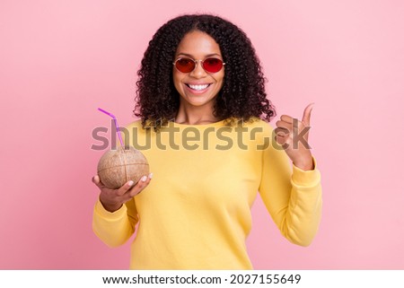 Photo of charming sweet dark skin woman wear yellow sweater drinking coconut water showing thumb up isolated pink color background