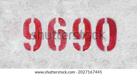 Red Number 9690 on the white wall. Spray paint. Number nine thousand six hundred ninety.