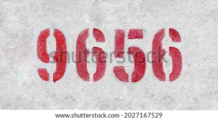 Red Number 9656 on the white wall. Spray paint. Number nine thousand six hundred fifty six.