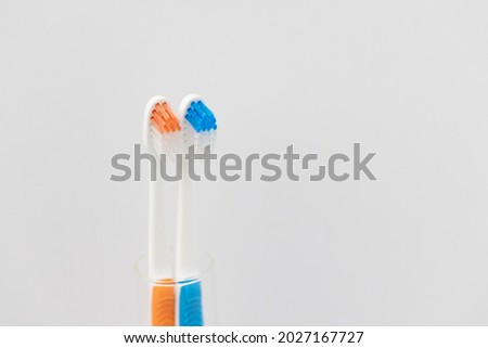 Orange and blue toothbrush in a glass