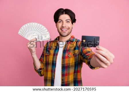 Photo of funky sweet young gentleman wear plaid outfit holding credit card dollars fan smiling isolated pink color background