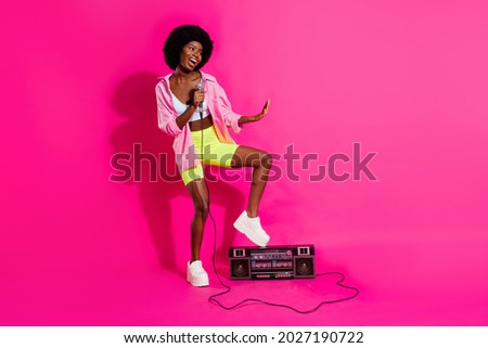 Photo of funky charming dark skin woman dressed crop top smiling singing mic boombox empty space isolated pink color background