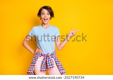 Photo portrait of screaming girl pointing finger at blank space with shirt on waist isolated on vivid yellow colored background