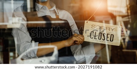 Women hand flip the sign to closed the shop.closed sign hanging on the glass door.