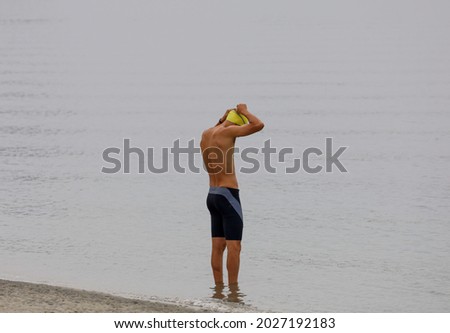 A young guy getting ready to go for a swim in the bay water.