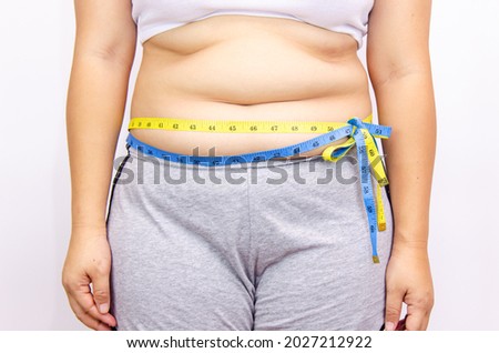 Beautiful fat woman with tape measure She uses her hand to squeeze the excess fat that is isolated on a white background. She wants to lose weight, the concept of surgery and break down fat under  Royalty-Free Stock Photo #2027212922