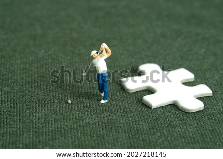 Miniature people toy figure photography. Winning tournament concept. A men golfer standing beside puzzle jigsaw at meadow field. Image photo