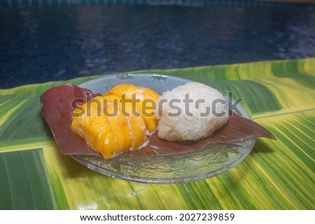 
Mango sticky rice served on a spotted banana leaf by the pool.
speckled banana leaves in the background.
beautiful green and yellow color of nature background. food and restaurant concept.
