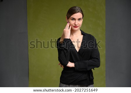 Cute female manager posing with a smile while standing on a dark green background.
