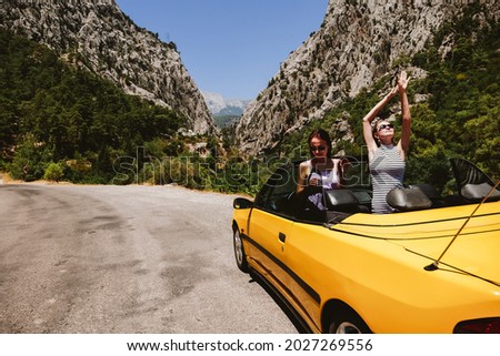 Two young pretty woman enjoying vacation on picturesque mountain view road