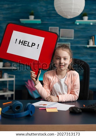 Conceptual image of elementary school kid with sign asking for help with assignments and homework for online internet classes and lessons. Small caucasian girl having creativity