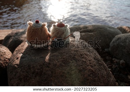 Fluffy handmade creatures outdoor. Fairy toys sit by the lake 