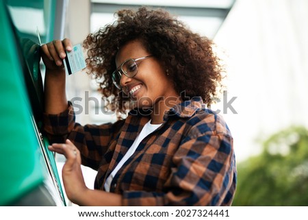Beautiful African girl using ATM machine. Happy smiling young woman withdrawing money from credit card.	