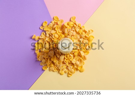 Tasty cornflakes and bottle of milk on color background