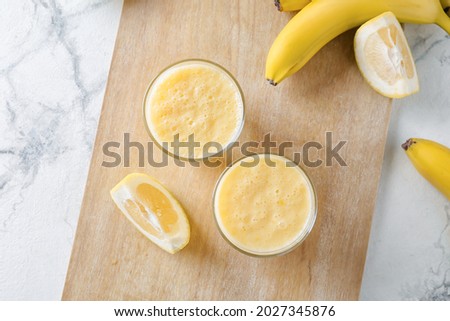 Glasses of tasty banana smoothie on light background