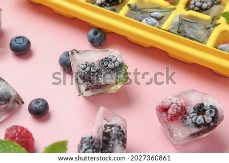 Ice with frozen berries on color background