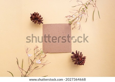 Brown Paper On A Pastel Yellow Background Decorated With Flowers And Fir Trees. Business card. Business Card, White Paper. Paper Mockups. Pastel Color Background
