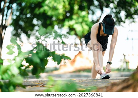Close up middle-aged Beautiful Sport Asian woman tying her shoelaces outdoors on beautiful summer day.