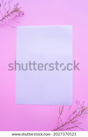 A4 White Paper On Pastel Pink Background With Floral Decoration. Vertical Photo, White Paper. Paper Mockups. Pastel Color Background
