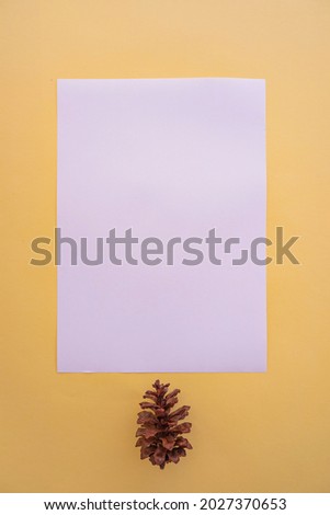 A4 White Paper On A Pastel Yellow Background With Spruce Flower Decoration. Vertical Photo, White Paper. Paper Mockups. Pastel Color Background
