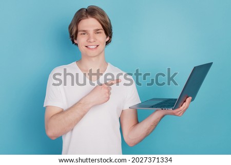 Portrait of smart guy holding point finger laptop working isolated over blue background