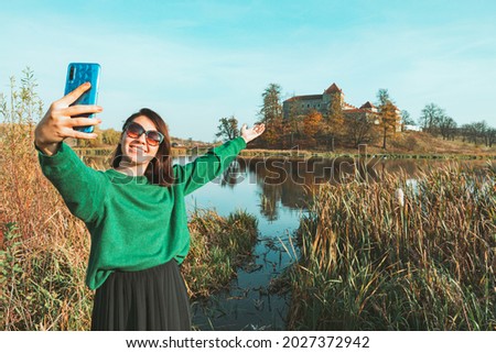 young pretty woman taking selfie picture in front of old castle. copy space. autumn season