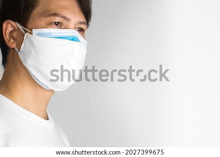 Thai man Close-up male face with a mask stacked double layers, white cotton, and blue paper. isolate
