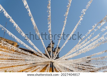 Street lamp decorated with white paper for the summer festivities of a Spanish town from a low perspective