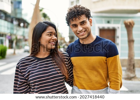 Young latin couple smiling happy and hugging at the city.